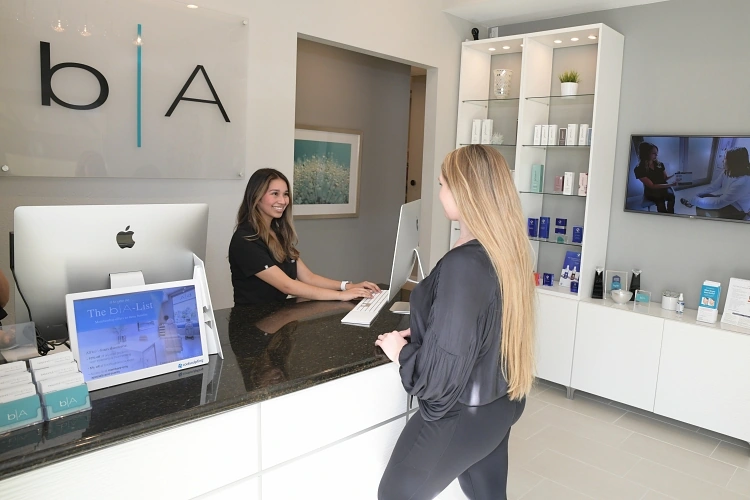 Young woman checking in with a friendly front desk staff at b|A